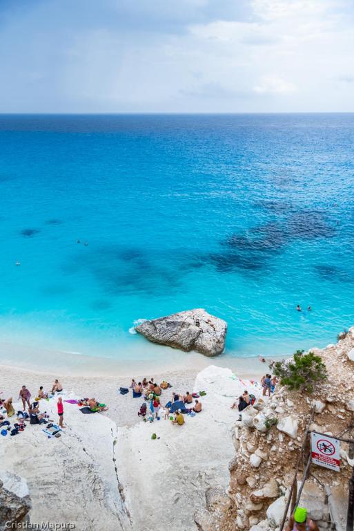 a group of people on a beach near the ocean at bilocale vista porto in Cannigione