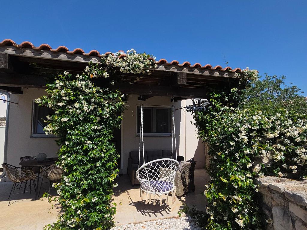 a pergola with a table and chairs and flowers at Apartment Dulcis Domus in Bale