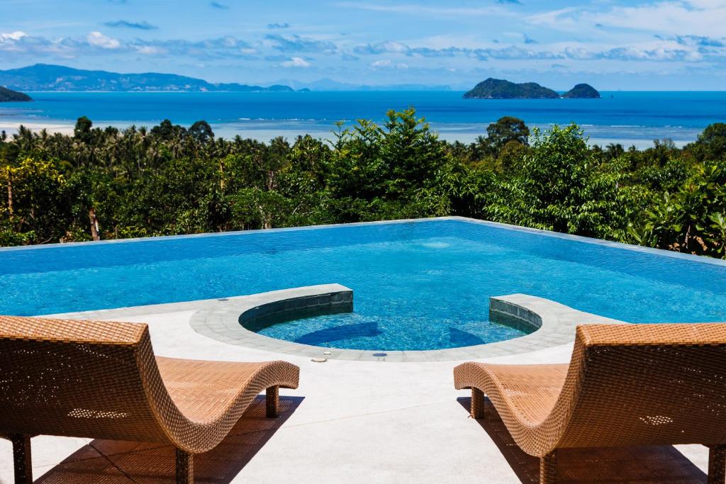 a swimming pool with two chairs and the ocean at Villa Pandora in Wok Tum