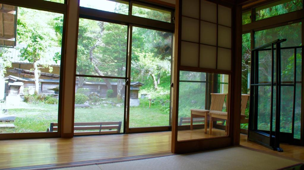 an empty room with large windows and a table at Tsumugu dom in Ueda