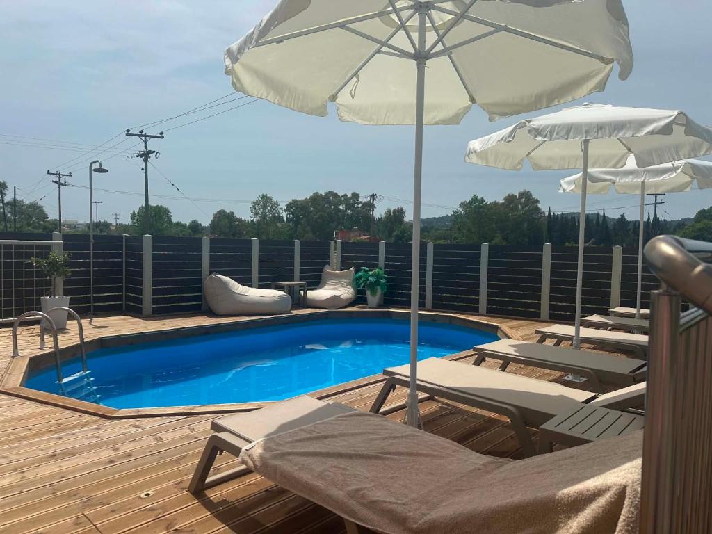 a pool with chairs and an umbrella on a deck at Evelina Luxury Suites with Swimming Pool in Corfu in Ipsos