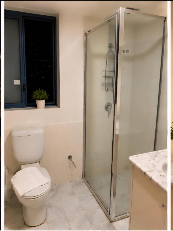 a bathroom with a toilet and a glass shower at Hobart city hotel in Hobart