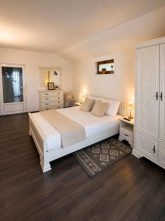 a bedroom with a large white bed and a dresser at Casuta Irinei in Gura Vadului