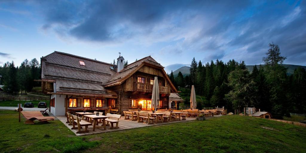 a large wooden house with tables and chairs at Ludlalm am Prebersee in Tamsweg