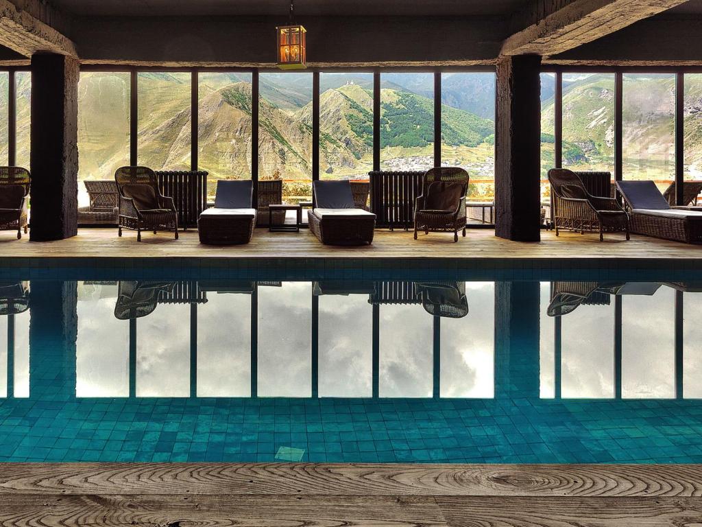 a swimming pool with chairs and a view of the mountains at Rooms Hotel Kazbegi in Kazbegi
