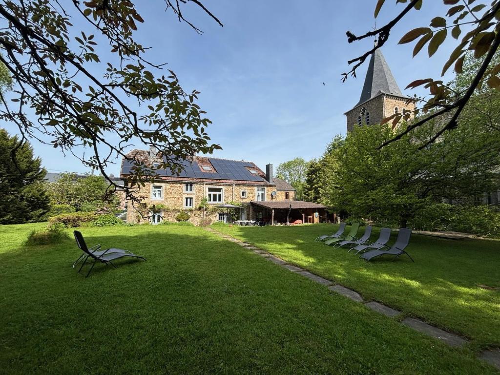 a group of chairs sitting in the grass in front of a building at B&B Les Soigneurs in Grandmenil