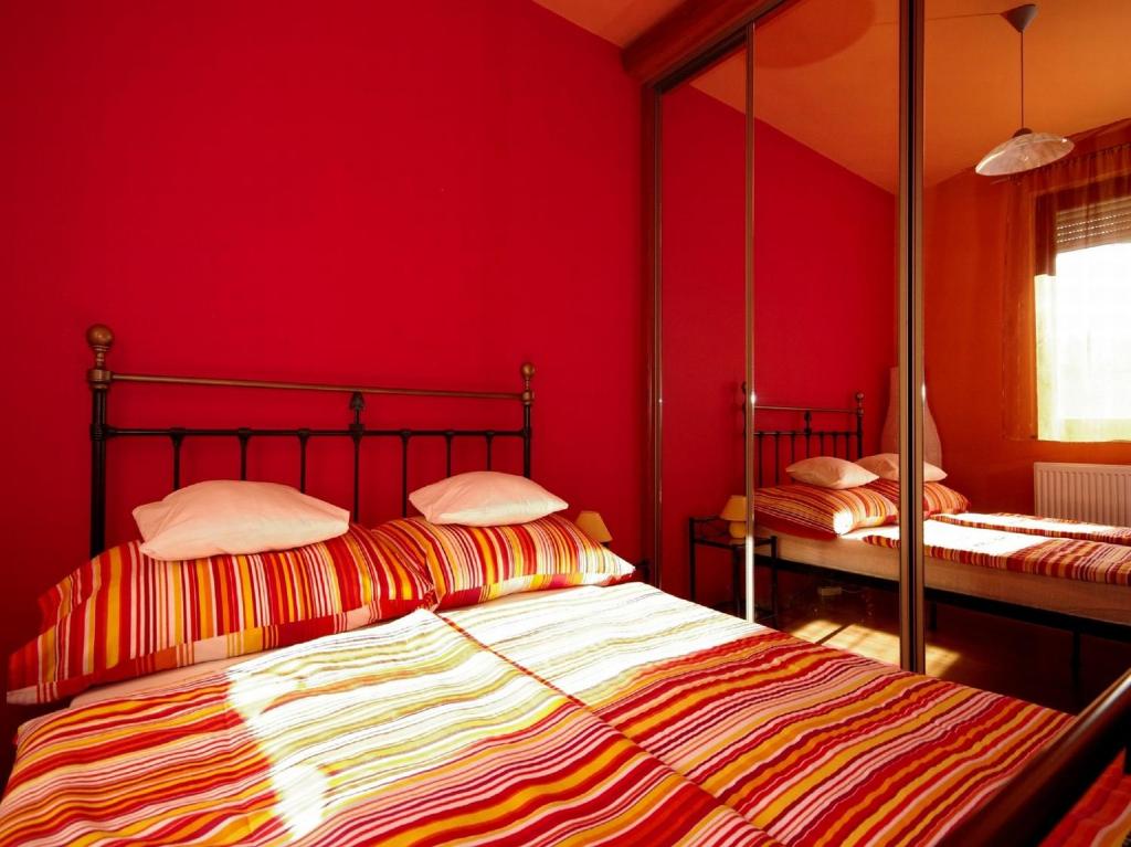 ジュラにあるHellasz Apartmanの赤い壁のベッドルーム1室(ベッド2台付)