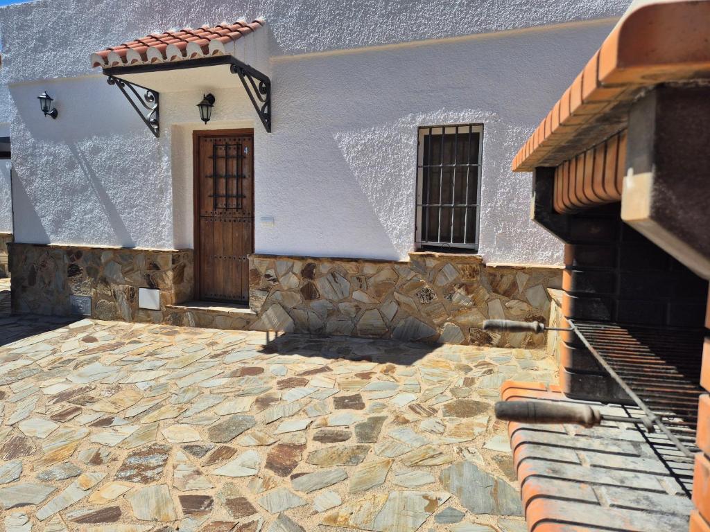 a white building with a door and a stone driveway at Cuevas La Cocinillas in Graena