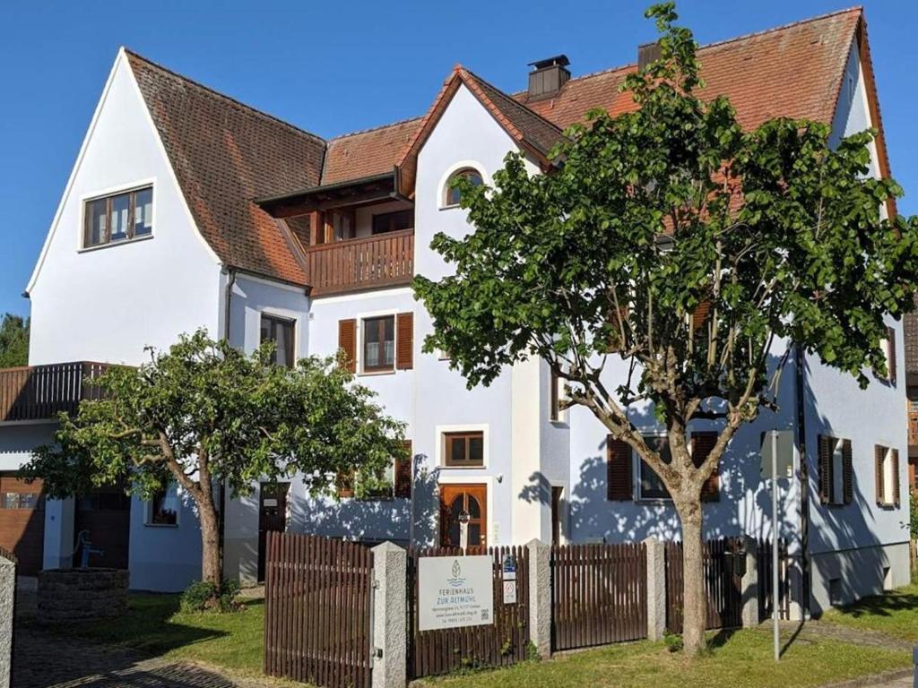 a white house with a fence and trees at Ferienhaus zur Altmühl - Ferienwohnungen & Gartenhäuser in Ornbau