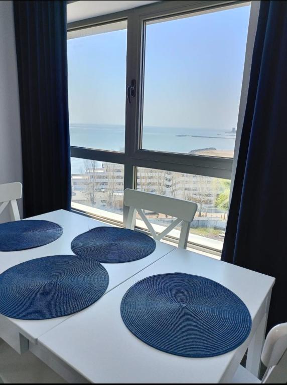 a table with three blue plates on it with a window at Olimp sea view in Olimp