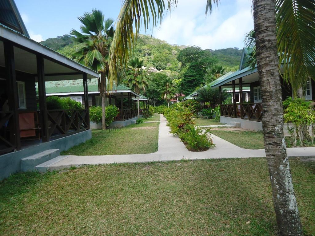 a walkway in front of a house with a palm tree at Chez Michellin Pensions Residence in La Digue