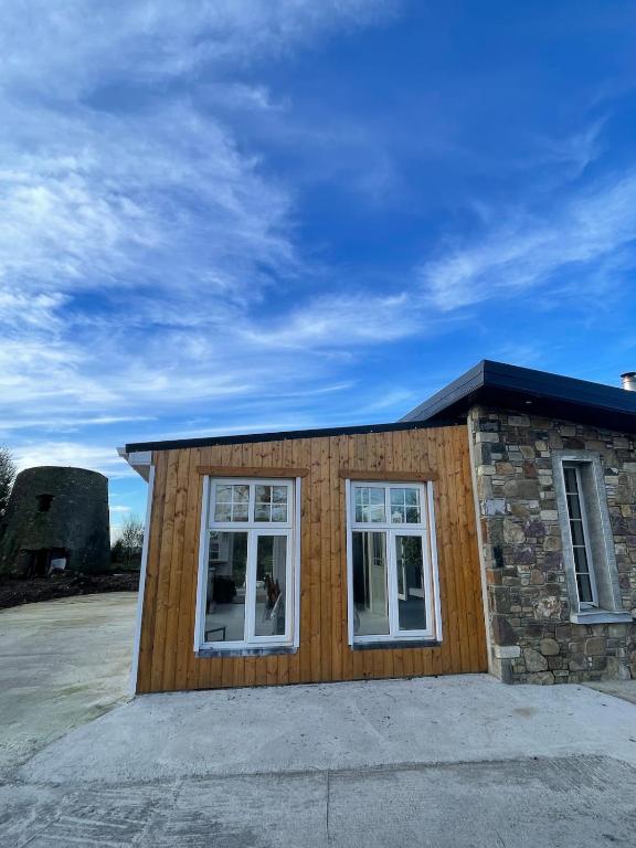 a small house with two windows and a stone wall at Mickeys Shed in Waterford