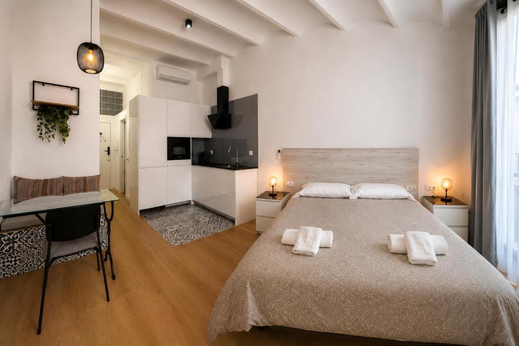 a white bedroom with a large bed and a desk at A H Rentals Monet estudio in Vinarós