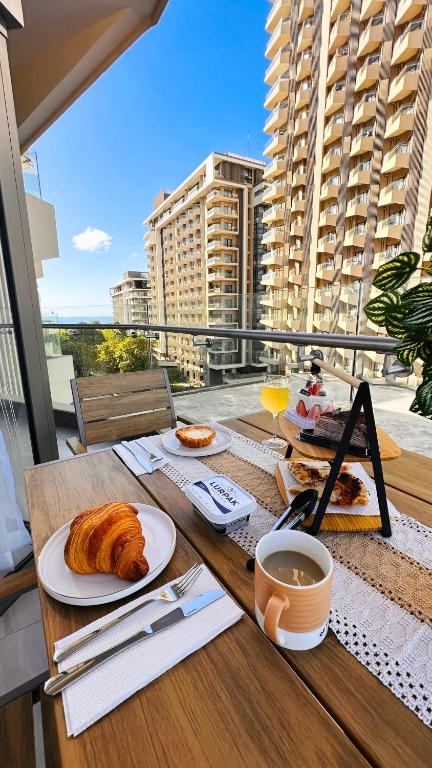 a table with a breakfast of croissants and coffee on a balcony at Resort Living 1BR Corner Apartment with Balcony in Maribago