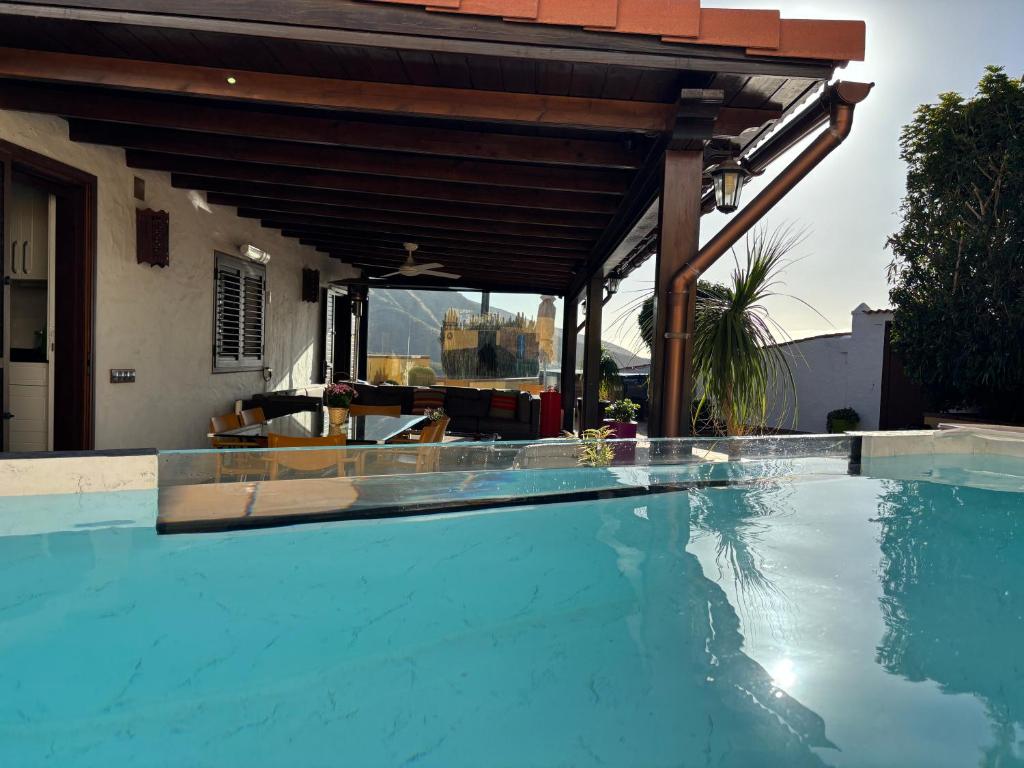 an outdoor swimming pool with a wooden pergola at Los Jazmines in Agaete