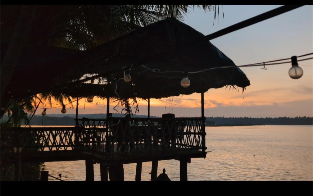 a dock with an umbrella and chairs on the water at Maleyam Homestay in Kozhikode