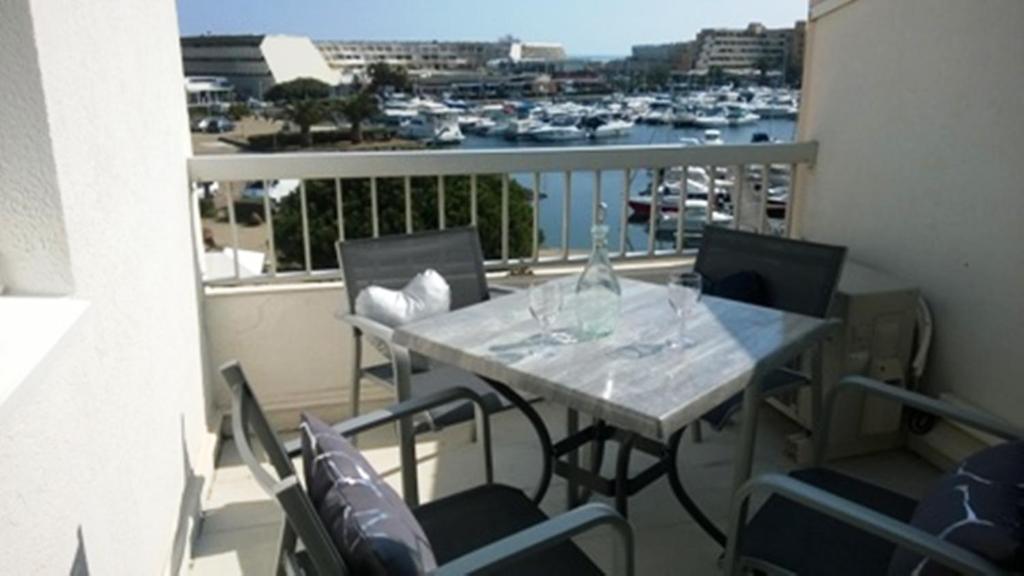 a table on a balcony with a view of a harbor at Port Soleil - Naturist Village in Cap d'Agde