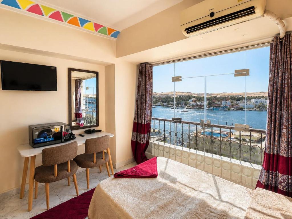 a room with a large window and a desk with a view at NubaNest GuestHouse in Aswan