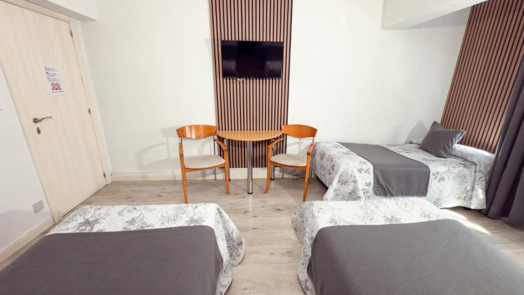 a room with two beds and a table and chairs at PENSIÓN PESQUERO in Burgos