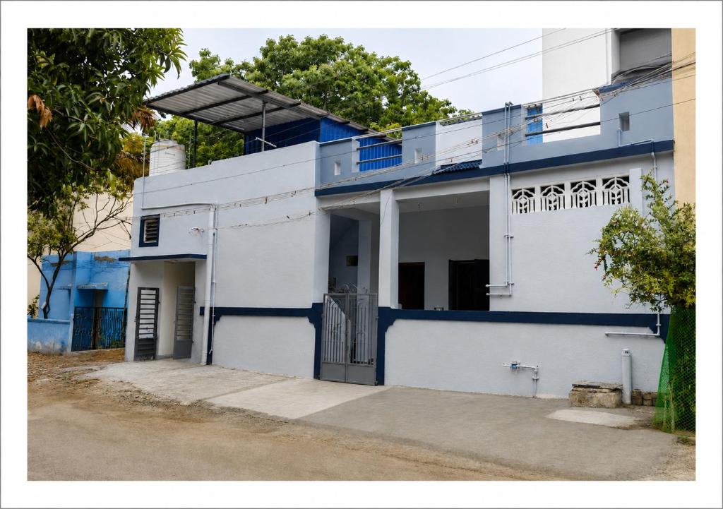 a blue and white building with a gate at Parisian Evenings Homestay - Madurai in Madurai