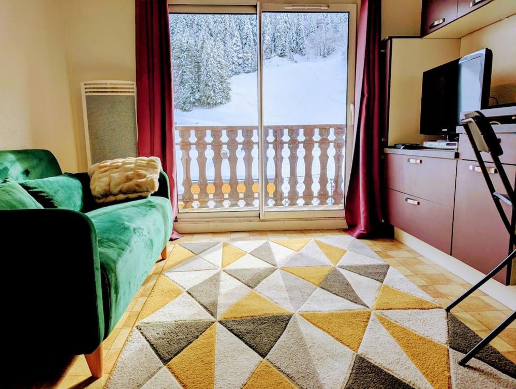 a living room with a couch and a large window at Les Portes du Soleil Studio in Le Biot