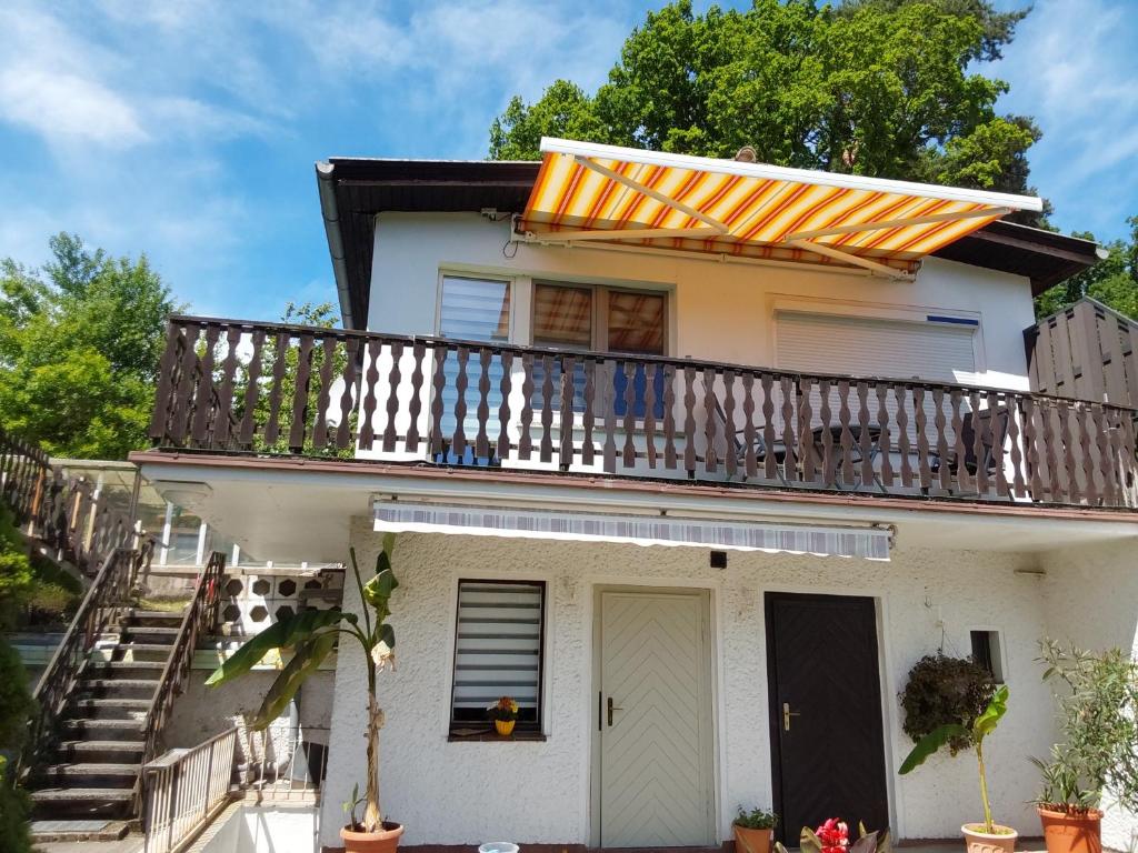 a white house with a balcony and stairs at Ferienwohnung Am See 55 in Bad Saarow