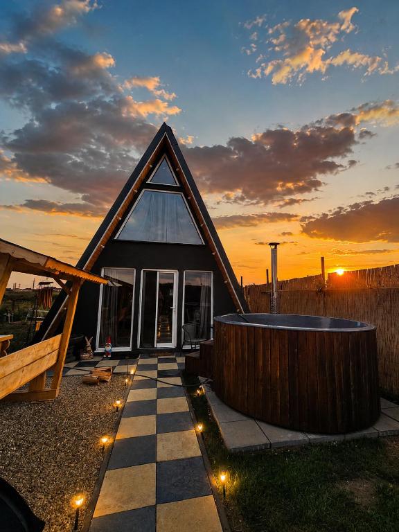 a house with a gambrel roof with a pool and a sunset at Elioan Cozy A-Frame in Mărăcineni