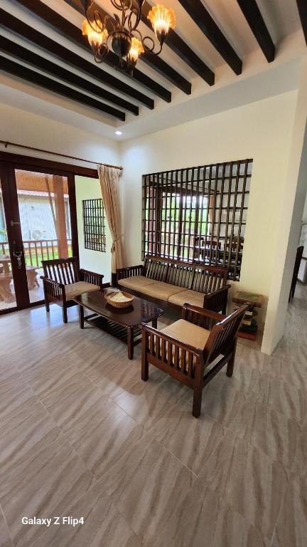 a living room with benches and a table and windows at Chaya village B - a shared pool & Jacuzi in Ko Lanta