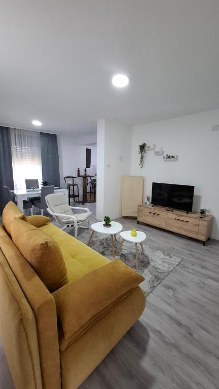 a living room with a yellow couch and tables at SAMI APARTMAN in Niš