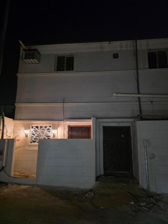 a white building with a gate and a door at night at نزل مشترك هوستيل in Khamis Mushayt