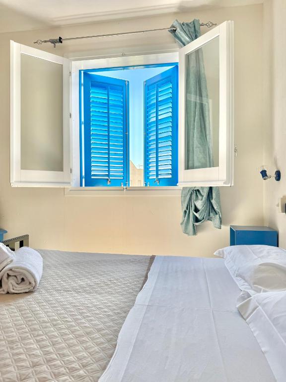 a bedroom with a window with blue shutters at Sulla Spiaggia in Marettimo