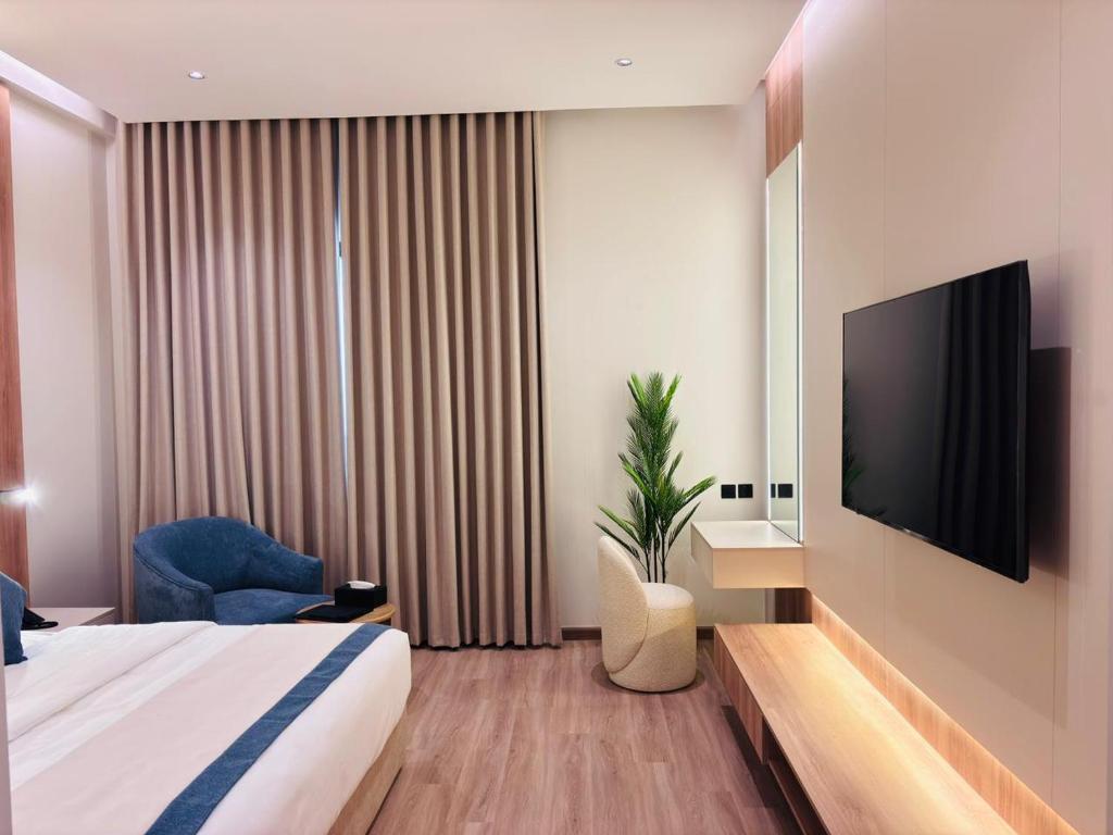 a hotel room with a bed and a flat screen tv at Voyage Expo Suites in Riyadh