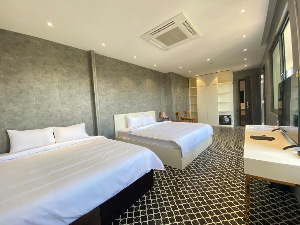 a hotel room with two beds and a desk at VMona Hotel in Thôn Kim Long (1)