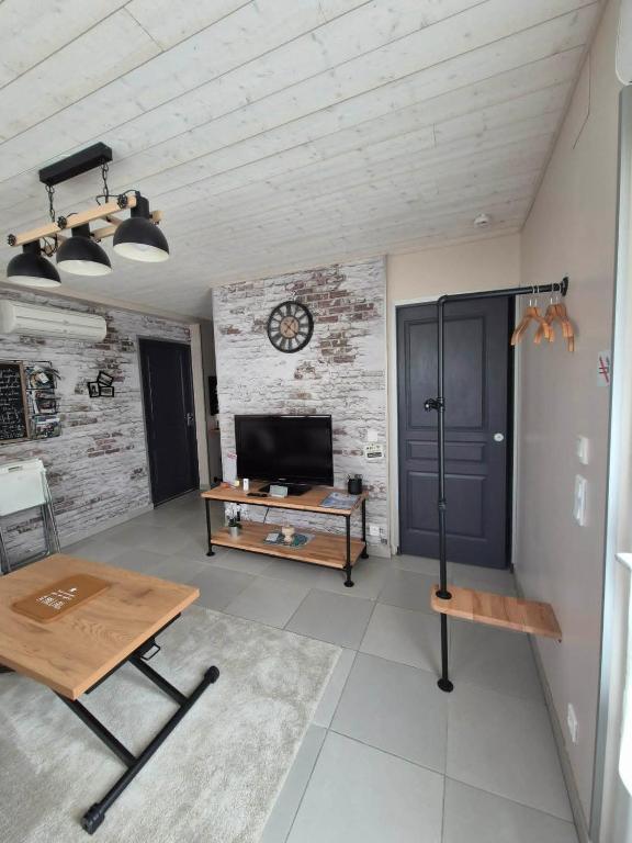 a living room with a table and a clock on the wall at Charmant appartement indépendant Ty-Oustal in Millau