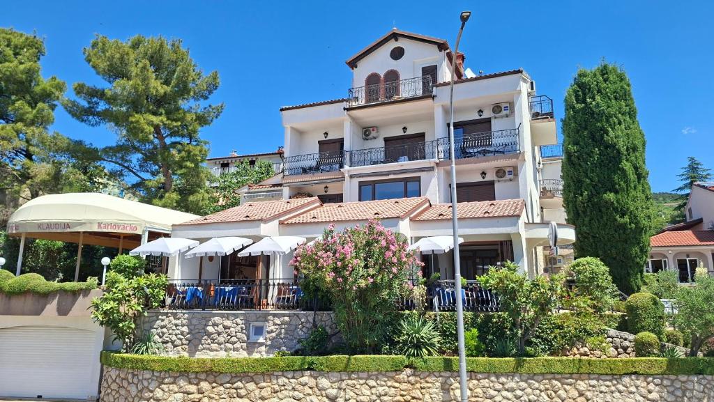 a building with chairs and umbrellas in front of it at Pansion Klaudija in Crikvenica