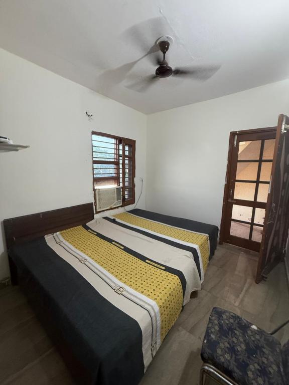two beds in a room with a ceiling fan at AC Room with attached bathroom and kitchen access in Zirakpur
