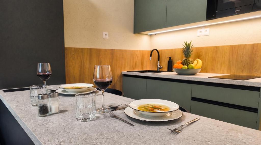 a kitchen with two plates of food and glasses of wine at Axiom Suites - Nova 7 in KoÅ¡ickÃ© KÃºpele