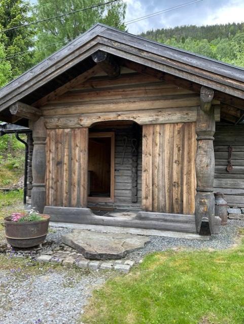 a small wooden cabin with a door in the grass at Liten hytte i Tinn in Notodden