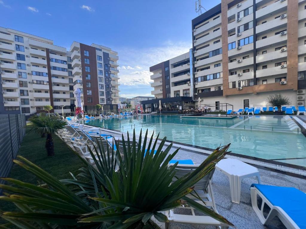 a large swimming pool with blue chairs and buildings at 85th Pool View Studio in Popeşti-Leordeni