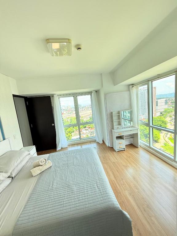a white bedroom with a large bed and large windows at trendy & Reliable Condo unit in Davao City