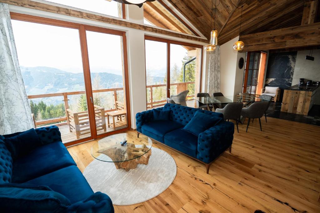 a living room with blue couches and a table at Frauenalmresort - Chalets in Sankt Lorenzen ob Murau