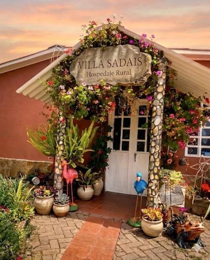 an entrance to a flower shop with plants and a sign at Hospedaje Rural Villa Sadais in Monguí