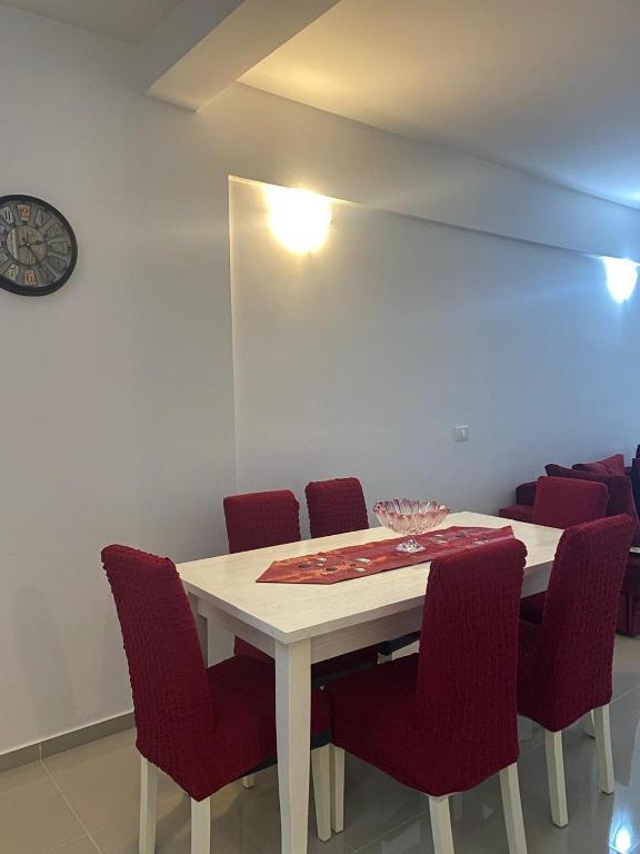 a dining room table with red chairs and a clock at Marina Luka in Bar
