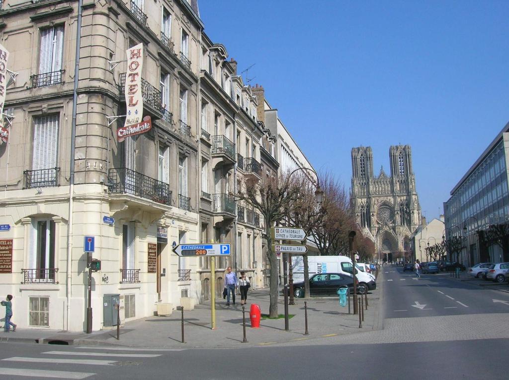 a building on a city street with a cathedral at Hôtel De La Cathédrale in Reims