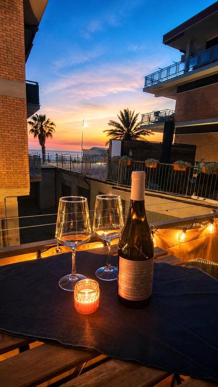 a bottle of wine and two glasses on a table at Oceanine 7 - Seaview Apartment in Lido di Ostia