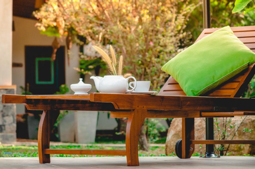 a wooden table with a green pillow and cups on it at Hotel Garcinia Leaf in Hikkaduwa
