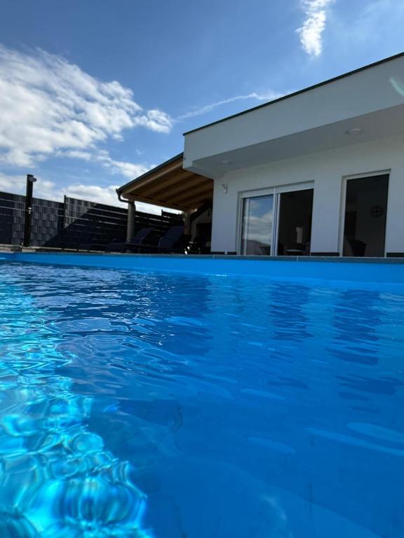 a swimming pool with blue water in front of a house at Kuća za odmor Ana in Prozor