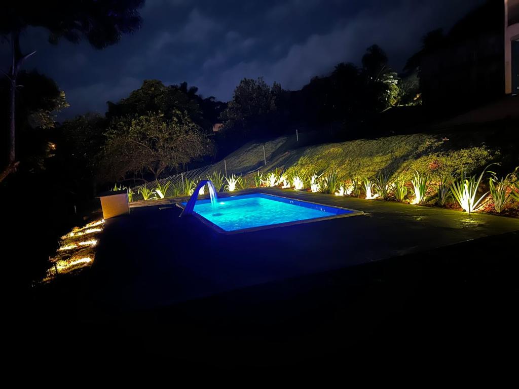 a swimming pool lit up at night with lights at Casa represa Piracaia in Piracaia