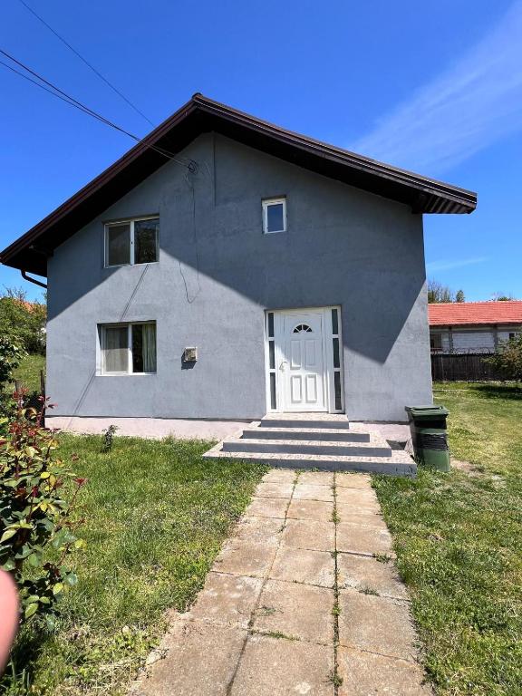 a gray house with a white door and grass at Vlădești house in Vlădeşti