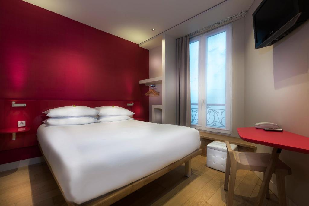 una camera con un letto bianco e una parete rossa di Hotel Andréa a Parigi